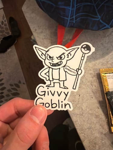 A customer holding their custom die-cut sticker featuring a black and white goblin illustration and the text 'Givvy Goblin'.