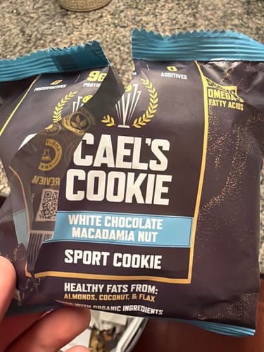 Reviewer holding two packages of the Cael's Cookie sport cookie.
