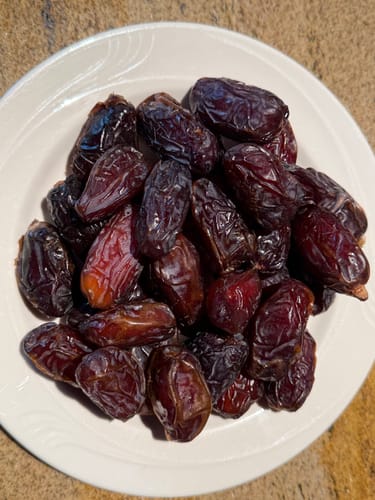 Customer's white plate piled high with plump Organic Premium Medjool Dates.