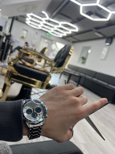 Close-up of a customer's wrist wearing the Lucky Fours® Chronometer with a white face and blue bezel in a salon.