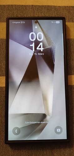 Rezensent zeigt die blasenfrei angebrachte Schutzfolie auf einem eingeschalteten Samsung-Handy.