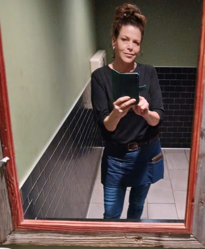 Customer taking a mirror selfie, showing off a full Premium Messy Bun in a stylish updo.