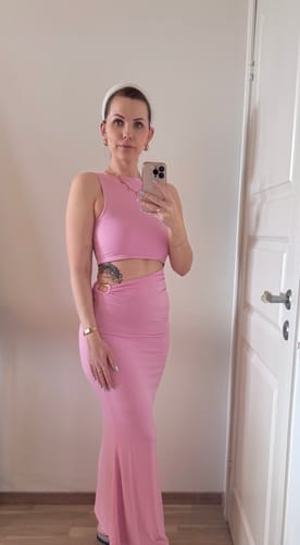 Reviewer in the sleek, pink Goddess Dress, showing the floor-length style and asymmetrical waist cut-out.