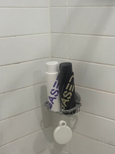 Customer's Shower Duo shampoo and conditioner in a metal shower caddy against a tiled wall.