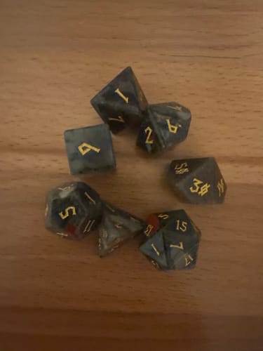 Customer's full African Bloodstone Stone Dice Set with gold numbering scattered on a wooden table.