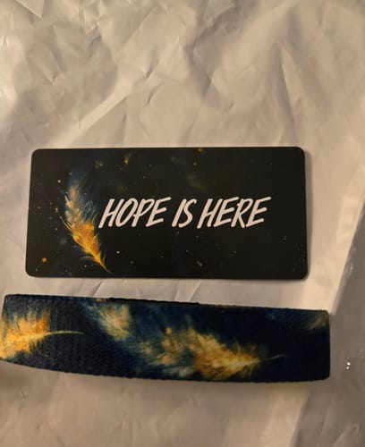Customer's Hope Is Here Bracelet with its feather pattern, next to a card that says 'HOPE IS HERE'.