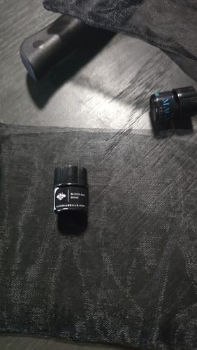 Customer's small bottle of Blood and Bone fragrance on a black mesh surface.