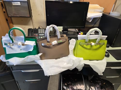 Reviewer's three colorful Warkin Bags in green, taupe, and lime green displayed on an office desk.