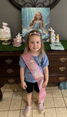 Customer's child celebrating her birthday with her personalized The Mermaid Princess portrait displayed on a dresser.