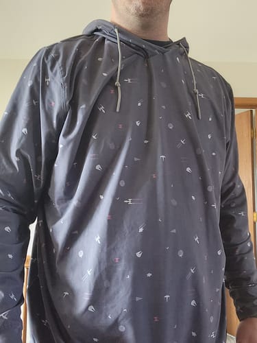 Reviewer showing the fit of the dark grey 'Stay on Target' hoodie with its Star Wars pattern.