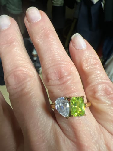 Reviewer wearing the Toi Et Moi Birthstone Ring with a green emerald-cut and a clear pear-cut stone.