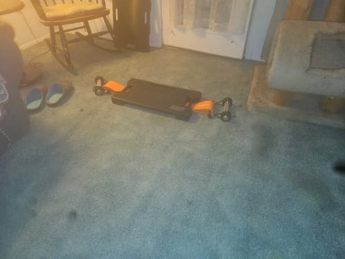 Reviewer's photo of a footplate with orange handles on a blue carpet, used for a trap bar deadlift.