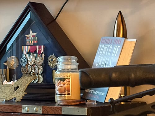 A reviewer's photo of a display shelf with military medals, a candle, and a book.