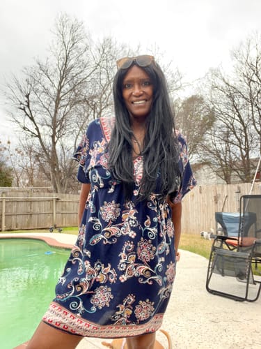Reviewer standing outdoors by a pool, wearing the long, black London Girl wig.