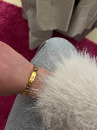 Rezensentin zeigt den goldenen Amore Zirconia Armreif an ihrem Handgelenk.
