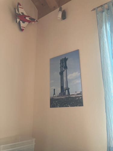 A customer's 'Ready for Launch' metal print hanging on a beige wall next to a blue curtain.