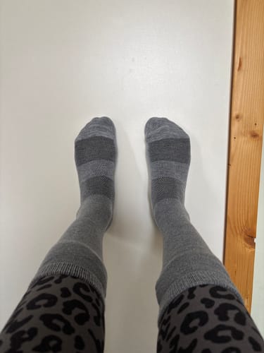 Customer's first-person view of their grey, striped Crew Socks worn over leopard-print leggings.