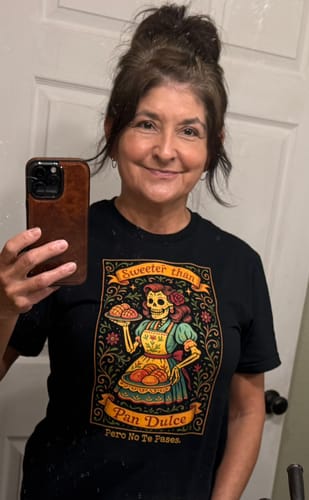 Reviewer smiling in a mirror selfie wearing the black 'Sweeter Than Pan Dulce Pero No Te Pases T-Shirt'.