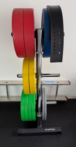 Ein Kunde zeigt die roten 25kg-Bumper-Plates auf einem Hantelscheibenständer zusammen mit anderen bunten Scheiben.