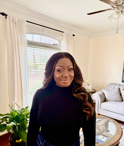 Reviewer smiling while wearing the Sensationnel Bare Lace Glueless Wig with long, soft waves.