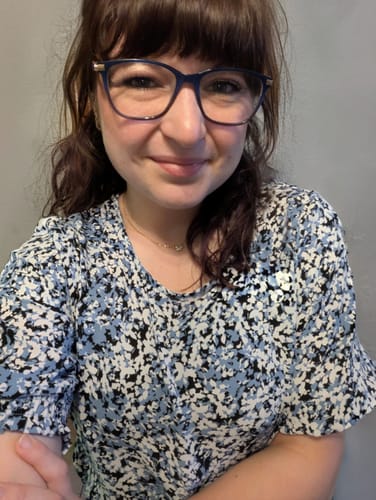 Reviewer smiles while wearing the dainty Tiffany Crystal Leaf Pendant Necklace with a floral top.