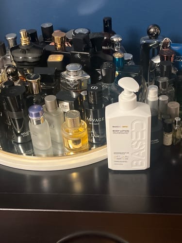 Customer's white Body Lotion bottle on a dresser in front of a large collection of colognes.