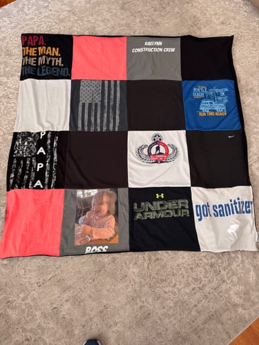 Customer's finished Project Repat T-Shirt Quilt laid flat, showing squares made from various colorful shirts and a photo.