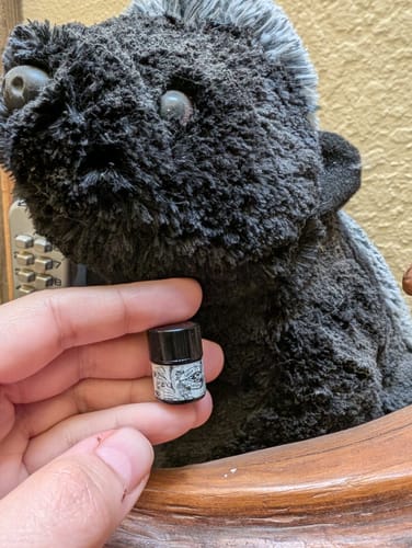 Customer holding a tiny sample vial of Sillage De La Sarigue in front of a stuffed opossum.