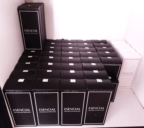 Reseña de cliente mostrando una colección de cajas de perfume Esencial, negras y blancas, en un estante.