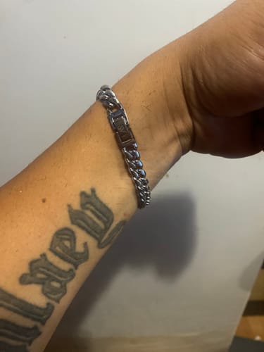 Un cliente muestra la Pulsera Cuban 8mm en su muñeca, que tiene un tatuaje en el antebrazo.