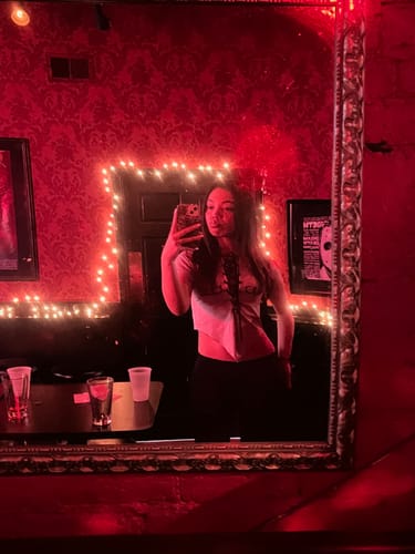 Reviewer taking a mirror selfie in a dark room, wearing the Matte Logo Tee with black pants.