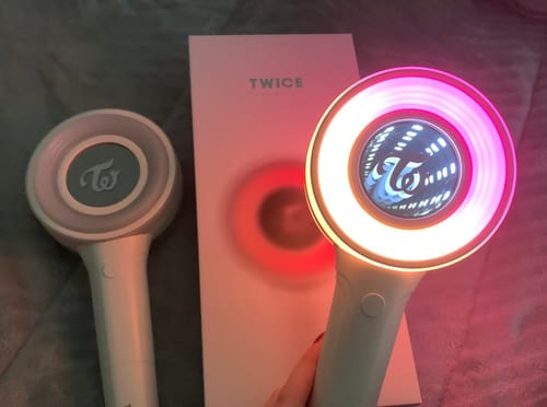 Customer's TWICE CANDYBONG ∞ light stick lit up pink, next to its box and an unlit light stick.