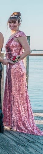 Reviewer's side view of the pink sequin cap-sleeve maxi dress, worn on a wooden dock by the water.