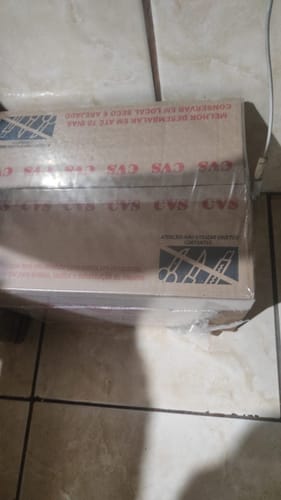 Caixa de papelão da Cesta Básica Jacarandá Plus do cliente, fechada e sobre um piso de cerâmica.