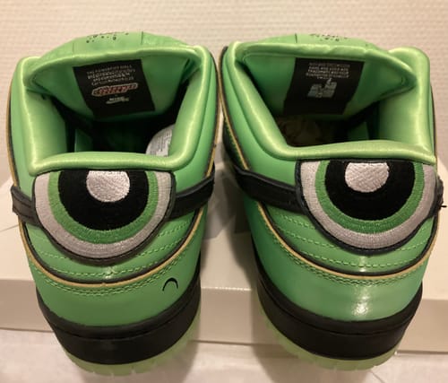 Achteraanzicht van de Nike SB Dunk Low Buttercup sneakers, met de geborduurde ogen van Buttercup op de hielen.