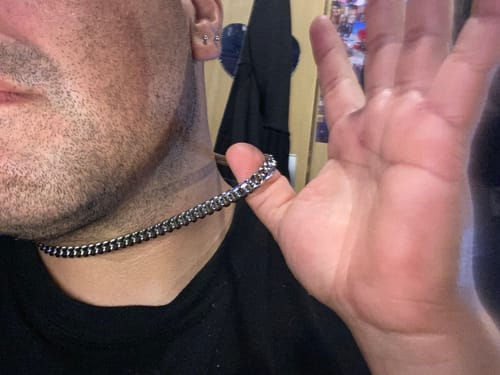 Un cliente muestra de cerca su cadena Cuban Link plateada de 8mm que lleva puesta.