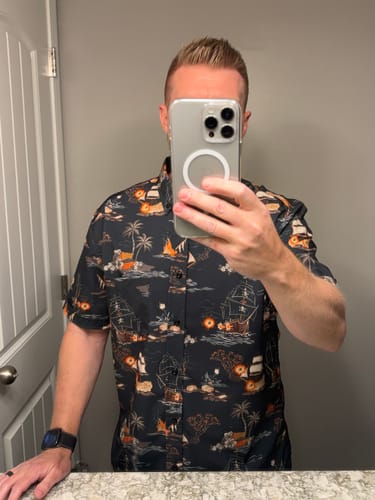 Reviewer taking a mirror selfie while wearing the dark, pirate-themed Days of Plunder shirt.