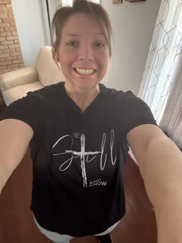Reviewer smiling while showing the comfortable fit of the black Ladies Whisper of Grace Tee.