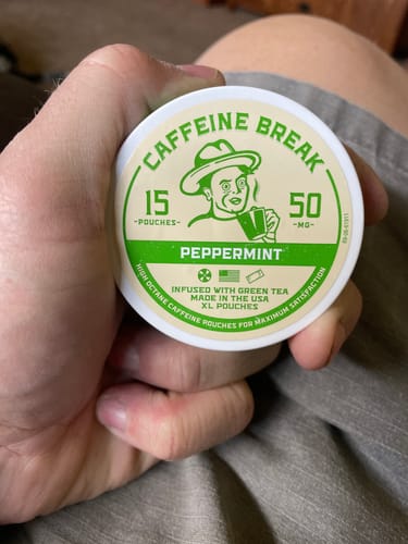 Customer holding the round, green-labeled tin of Caffeine Break Peppermint Caffeine Pouches.