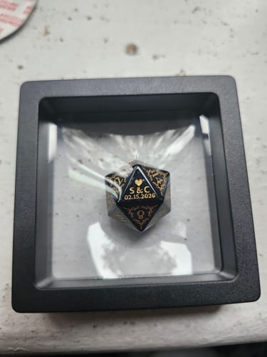 Customer's custom black die in its display case, showing initials 'S&C' and the date '02.15.2026' engraved in gold.