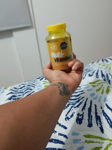 Cliente sostiene el frasco de Gomas con Multivitamínicos y Minerales, mostrando su etiqueta amarilla.