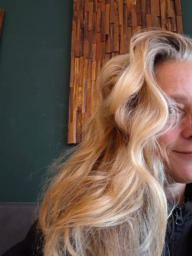 Nahaufnahme vom langen, welligen Haar einer Kundin, das trocken wirkt und im Kontext der Ylang-Ylang-Glow Haarseife bewertet wird.