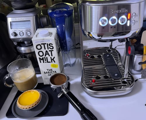 Reviewer's ground Brazil Santos coffee in a portafilter, with a brewed coffee and a tart.