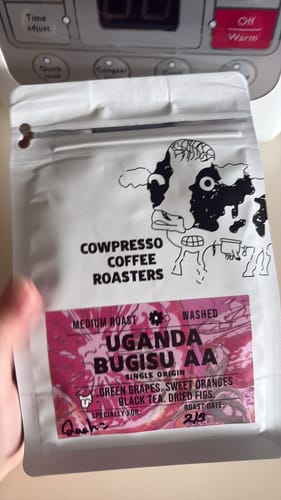 Customer holding the white bag of Cowpresso Coffee Roasters' Uganda Bugisu AA coffee beans.