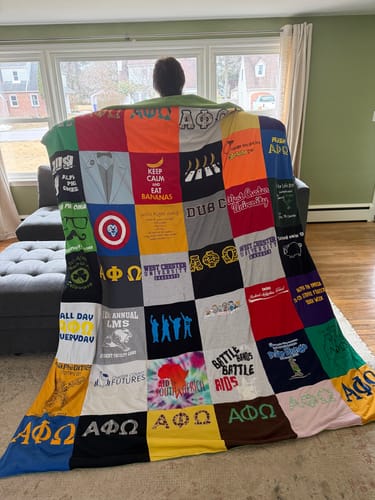 Reviewer holding up their large Project Repat T-Shirt Quilt, showing a colorful patchwork of shirt designs.