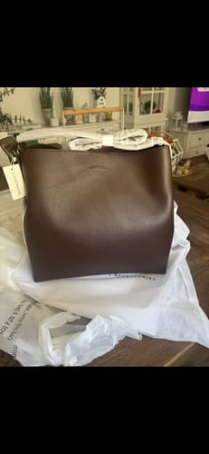 Customer's chocolate Peyton Shoulder Bag freshly unboxed and sitting on its white dust bag on a table.