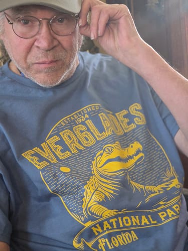 Close-up of a reviewer wearing the blue Everglades National Park Vintage Tee with a yellow alligator graphic.