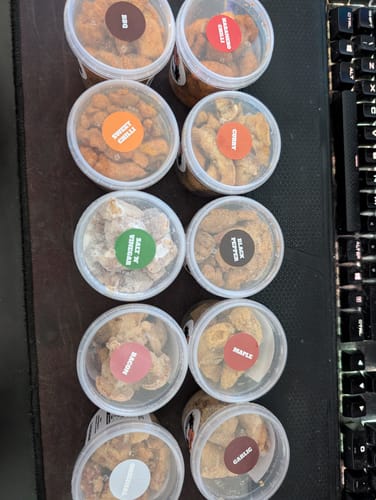 Reviewer's overhead photo of the Pork Scratching Taster Package, showing the 10 different flavour tubs.