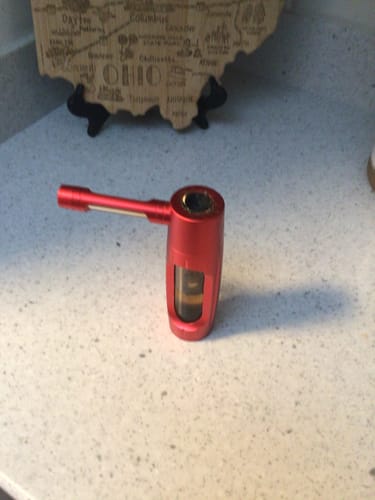 Reviewer shows a red metal pipe they use for the Purple Punch product, sitting on a counter.