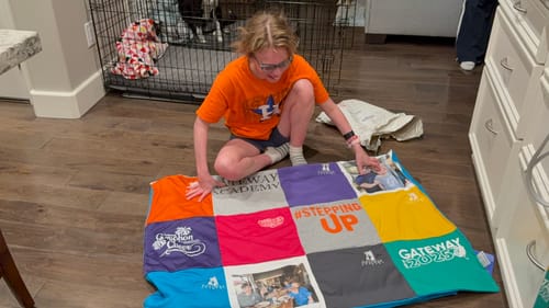 Reviewer shows a person admiring a new Project Repat T-Shirt Quilt on a wooden floor.